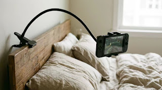 Lamicall gooseneck tablet mount holding a Nintendo Switch above a bed for ergonomic gaming.