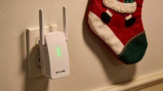 P-Link WiFi 6 extender plugged in wall outlet to boost signal for guest bedroom.