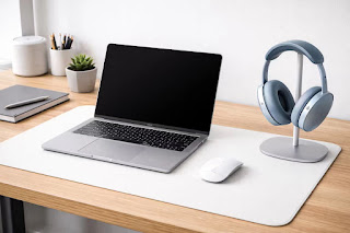 Apple AirPods Max blue on a stand next to a MacBook Pro.