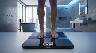 Withings Body Comp digital scale in a luxury bathroom setting, known for measuring vascular age and nerve health alongside body composition.
