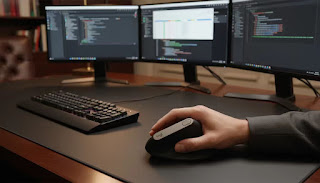 The premium Logitech MX Vertical Wireless Mouse featured in a professional, multi-monitor workstation setup.