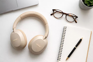 Bose QuietComfort Ultra headphones flat lay with glasses.