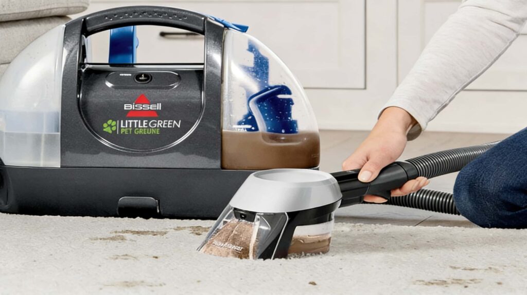 Close-up action shot of the Bissell Little Green's nozzle extracting dark, dirty water from a light-colored carpet, demonstrating its powerful deep-cleaning capability.