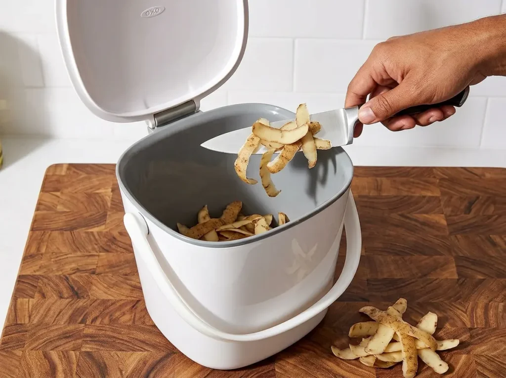 OXO Good Grips Easy-Clean Compost Bin with a stay-open lid on a butcher block counter.