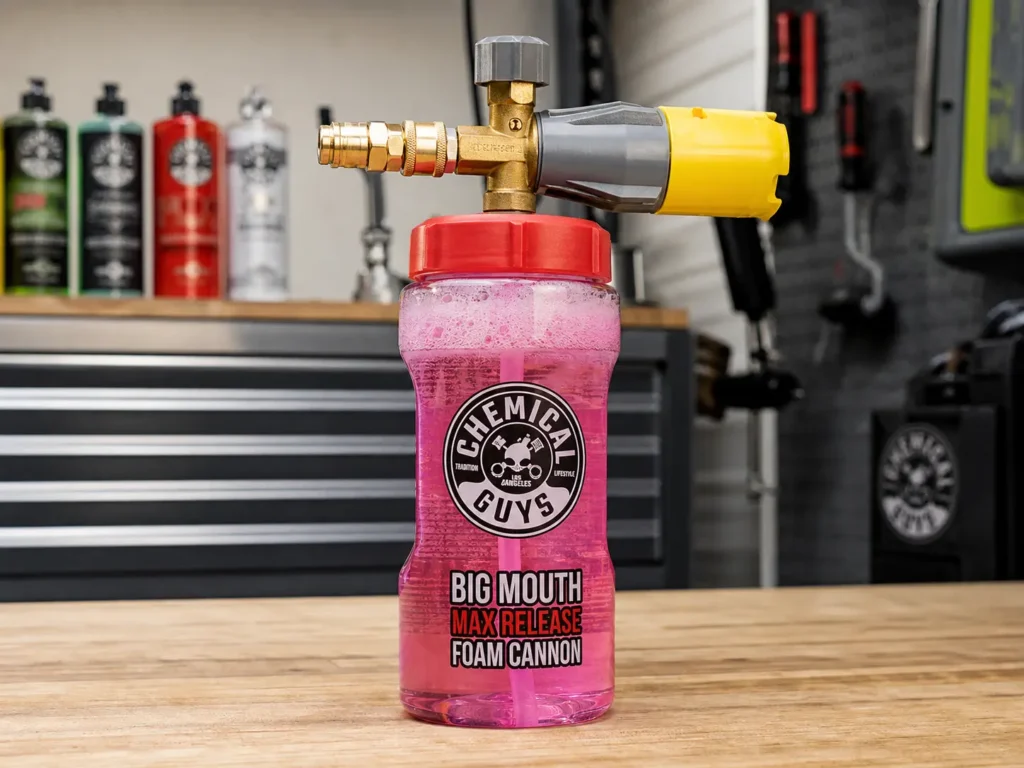 The Chemical Guys Big Mouth Max Release Foam Cannon standing on a wooden workbench with pink soap visible inside.