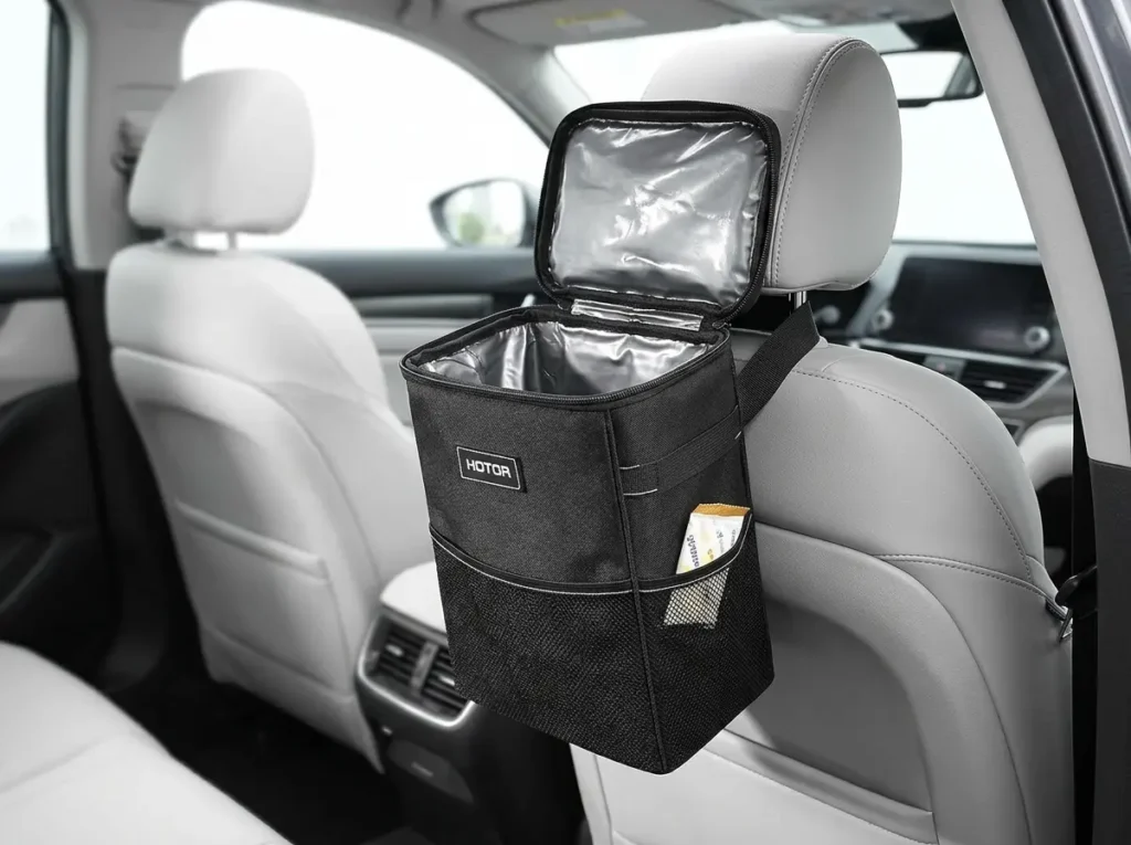Black HOTOR 2-gallon car trash can with side pockets and lid installed in a family car interior.
