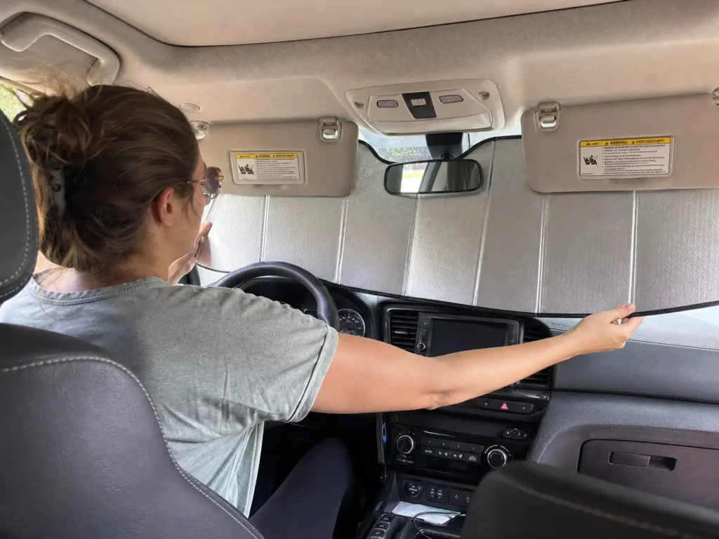 Installing a foldable windshield sun shade by securing it under car visors