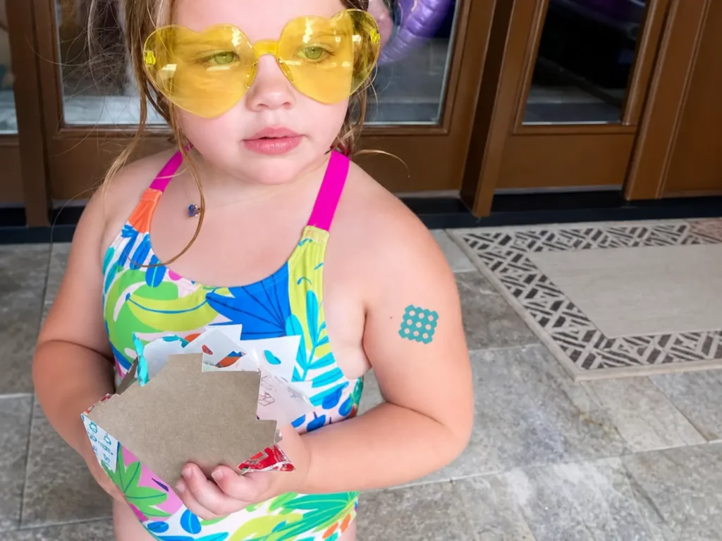 A collection of colorful, child-friendly NATPAT BuzzPatch bug bite relief patches featuring cute cartoon animal faces on a bright summer background.