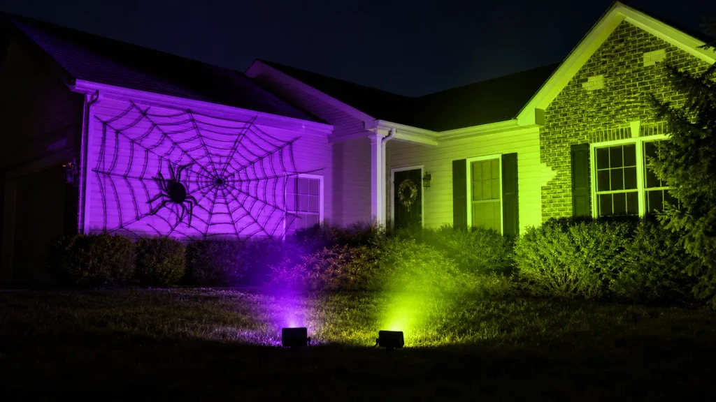 MELPO 50W RGB outdoor flood lights illuminating a giant Halloween spider display in vivid purple and green.